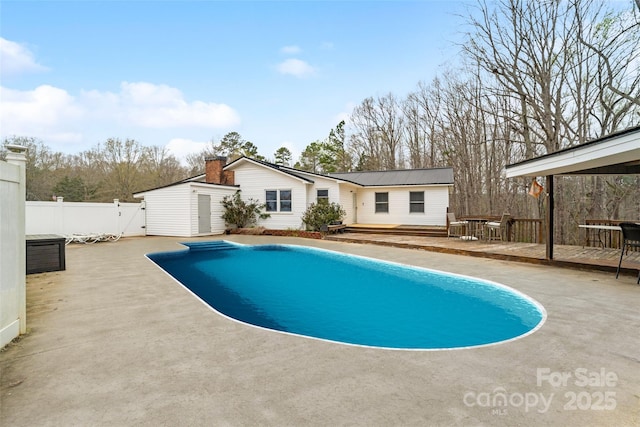 view of pool with fence, a wooden deck, a fenced in pool, a storage unit, and an outbuilding