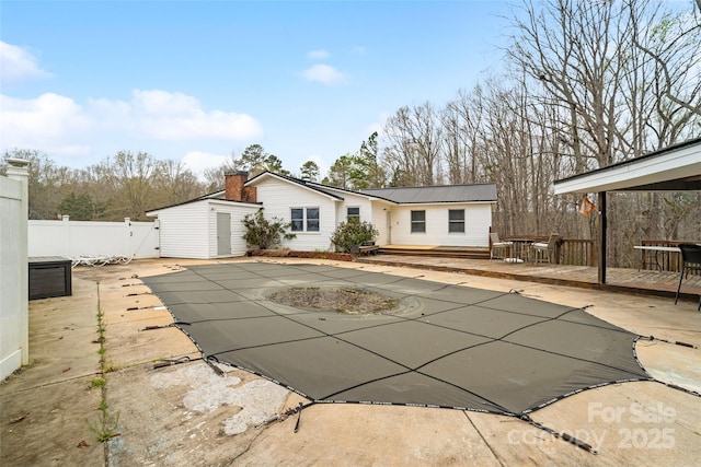 rear view of house featuring a shed, a wooden deck, fence, an outdoor structure, and a patio