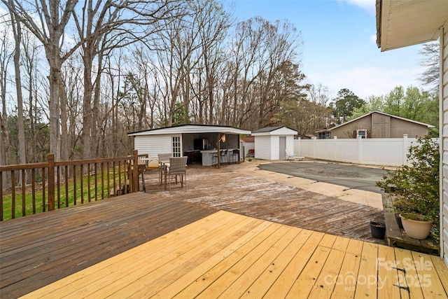 wooden deck featuring fence, a storage shed, and an outdoor structure