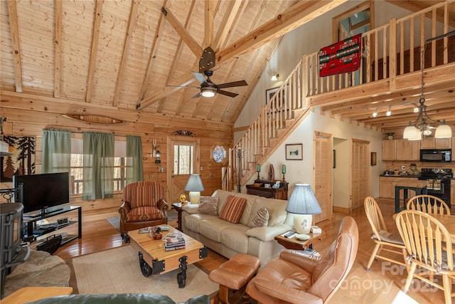 living area featuring wooden walls, light wood finished floors, a ceiling fan, and stairs