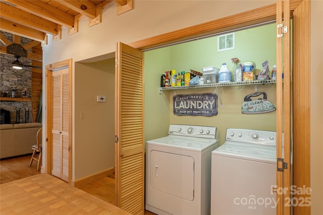 washroom with a fireplace, washing machine and dryer, visible vents, laundry area, and wood finished floors