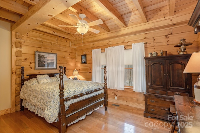bedroom with wood walls, light wood-style floors, wooden ceiling, and beam ceiling