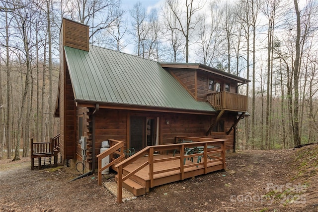 back of house featuring metal roof and a chimney