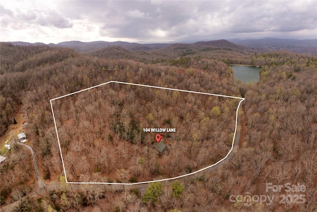 drone / aerial view with a forest view and a water and mountain view