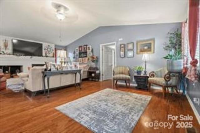 living room featuring lofted ceiling, wood finished floors, ceiling fan, and a fireplace