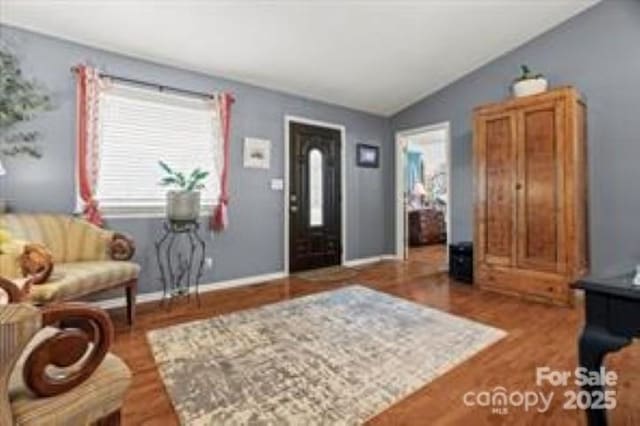 foyer featuring baseboards, lofted ceiling, and wood finished floors