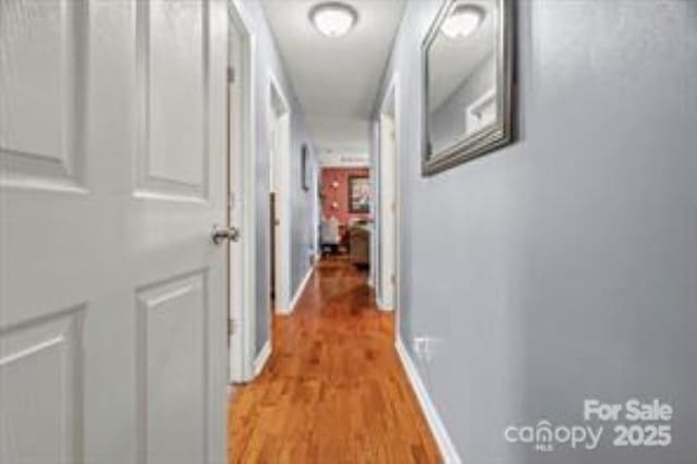 hall with baseboards and light wood-style floors
