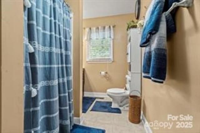 bathroom featuring baseboards, toilet, and a shower with shower curtain