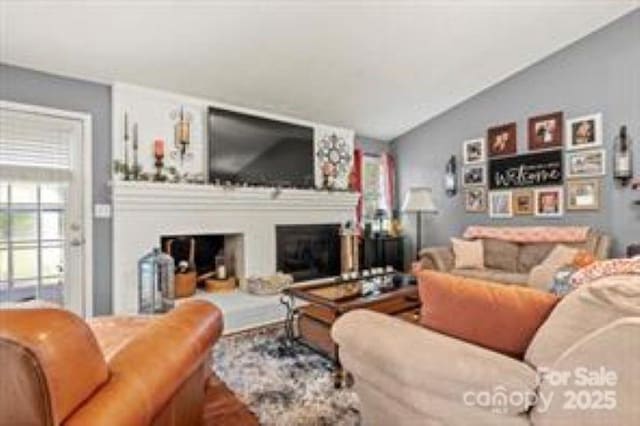 living room featuring a glass covered fireplace and lofted ceiling