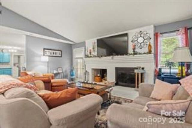living room featuring vaulted ceiling and a glass covered fireplace