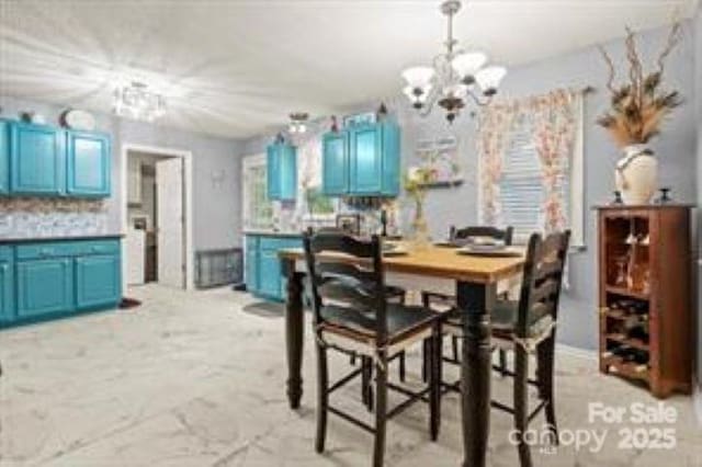 dining space featuring marble finish floor and a chandelier