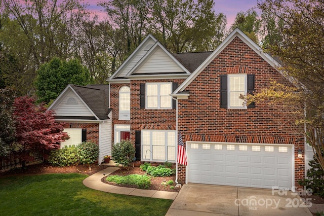 traditional-style house featuring a front lawn, an attached garage, brick siding, and concrete driveway