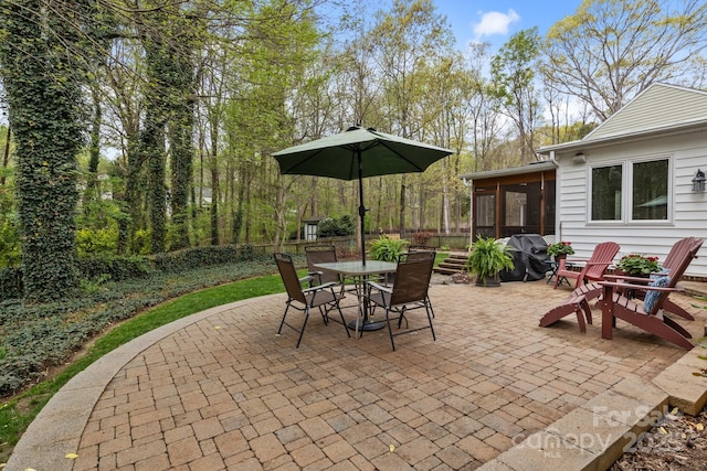 view of patio with a grill, outdoor dining area, and a sunroom