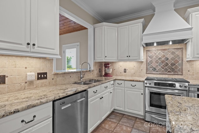 kitchen with premium range hood, ornamental molding, a sink, white cabinets, and appliances with stainless steel finishes