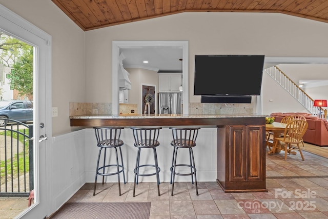 kitchen featuring wood ceiling, stainless steel fridge, backsplash, and vaulted ceiling