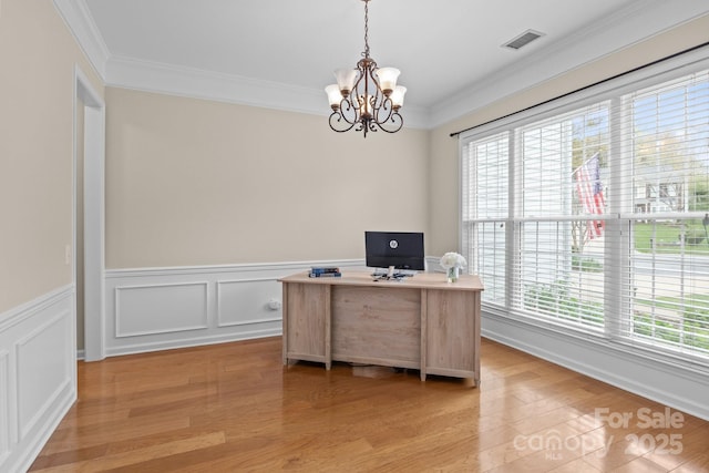 home office with crown molding, light wood-style floors, visible vents, a notable chandelier, and wainscoting