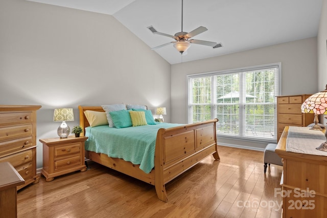 bedroom with a ceiling fan, vaulted ceiling, and light wood finished floors