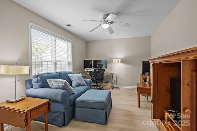 living room with baseboards, light wood-style floors, ceiling fan, and visible vents