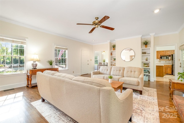 119 Lakenheath Ln, Matthews, NC 28105 - living area with visible vents, baseboards, ornamental molding, ceiling fan, and light wood-style floors