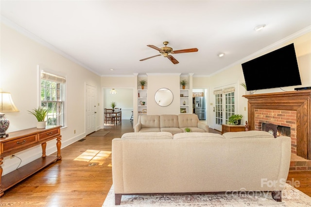 119 Lakenheath Ln, Matthews, NC 28105 - living area featuring built in features, a brick fireplace, ornamental molding, ceiling fan, and light wood-style floors