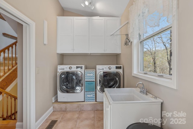 clothes washing area with washer and dryer, visible vents, baseboards, and cabinet space