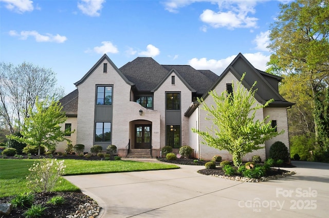 french country inspired facade featuring a front lawn, brick siding, and roof with shingles