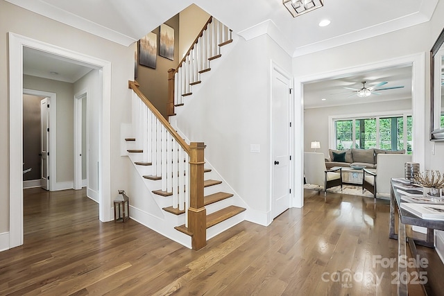 staircase with baseboards, ornamental molding, wood finished floors, and ceiling fan