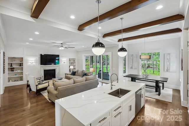 kitchen with dark wood finished floors, beamed ceiling, plenty of natural light, and a sink