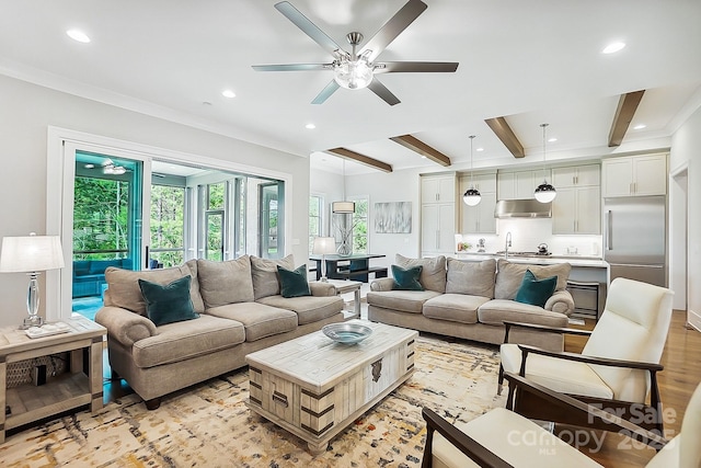 living area with beam ceiling, a ceiling fan, light wood finished floors, recessed lighting, and ornamental molding