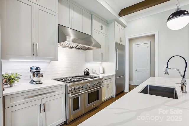 kitchen with decorative backsplash, range hood, a sink, decorative light fixtures, and high quality appliances