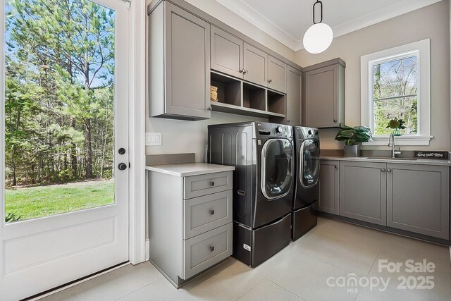 washroom with light tile patterned floors, a sink, washer and clothes dryer, and cabinet space