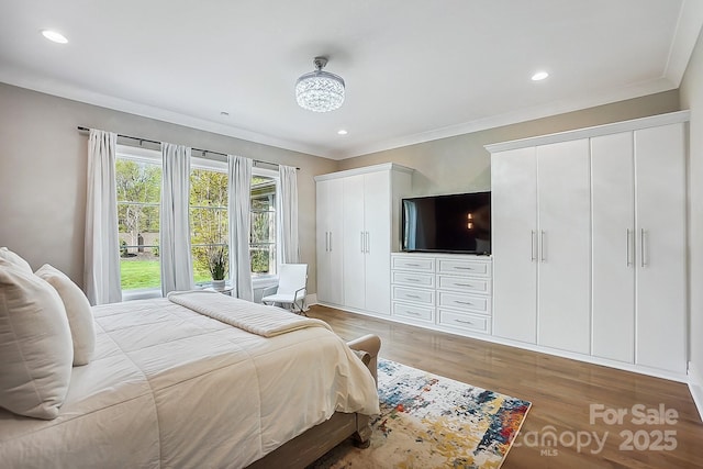 bedroom featuring recessed lighting, multiple closets, crown molding, and light wood-type flooring