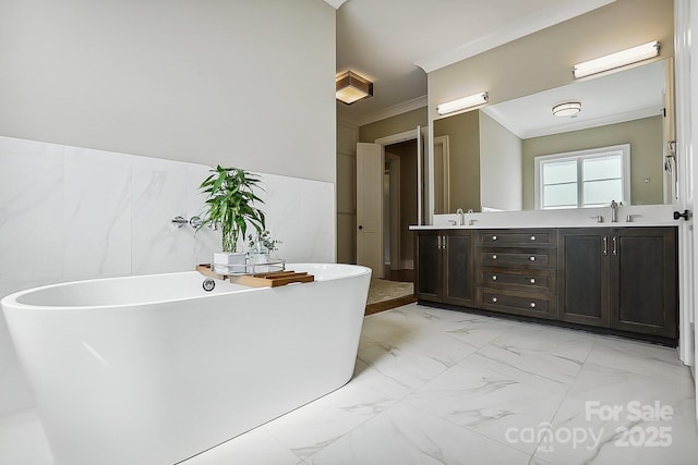 full bath with a soaking tub, crown molding, marble finish floor, double vanity, and a sink