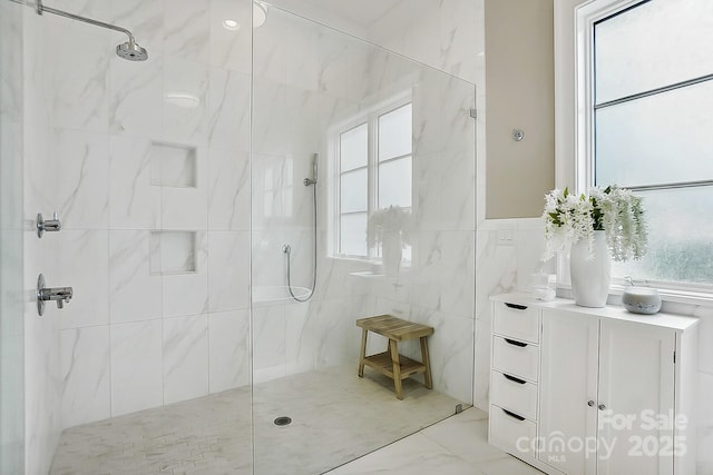 full bath with marble finish floor, tile walls, vanity, and walk in shower