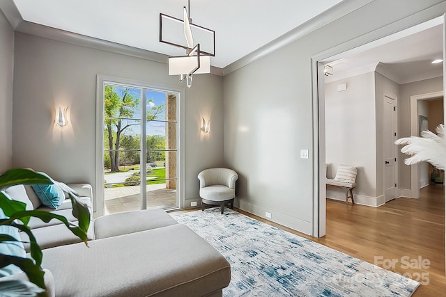 sitting room featuring baseboards, a notable chandelier, crown molding, and light wood-style floors