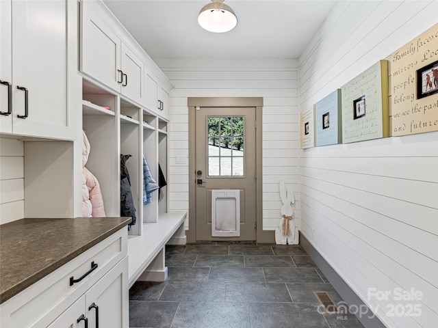 mudroom with wooden walls and stone finish floor