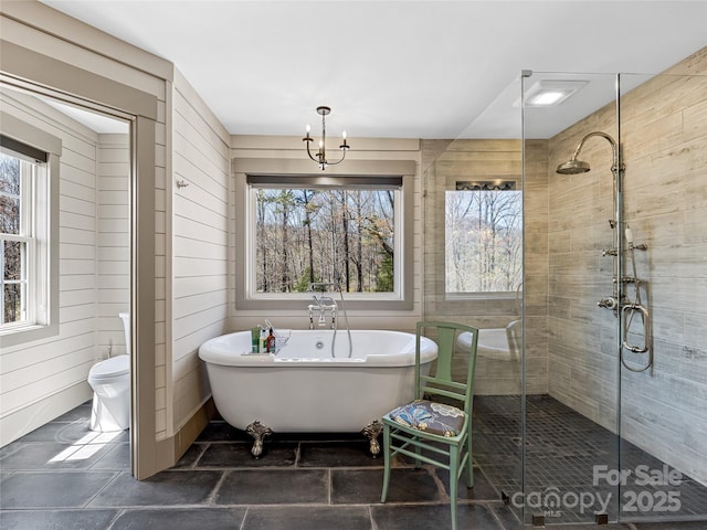 full bath featuring plenty of natural light, a freestanding tub, a chandelier, and a shower stall