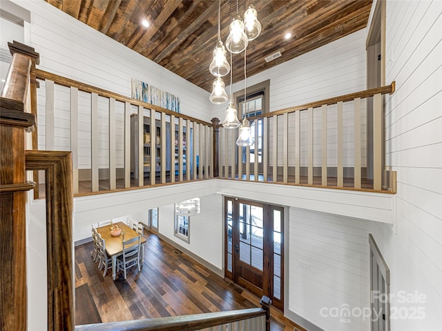 entrance foyer featuring wooden walls, a notable chandelier, wooden ceiling, visible vents, and hardwood / wood-style flooring