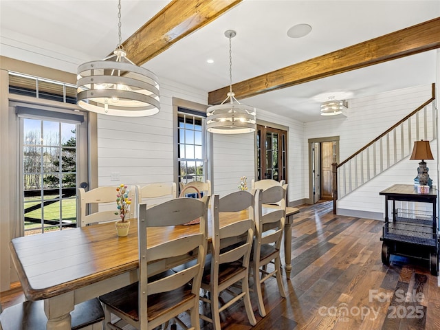 dining area with beam ceiling, stairway, a notable chandelier, wooden walls, and dark wood-type flooring
