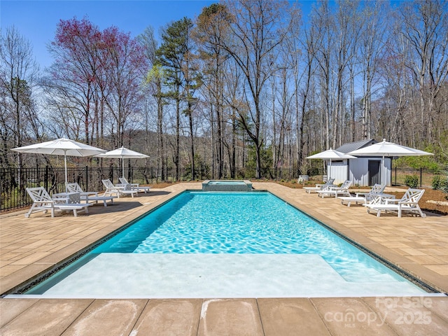 view of swimming pool with a patio, an outdoor structure, fence, and a pool with connected hot tub