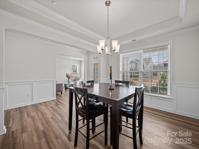 9582 Creighton Rd NW, Concord, NC 28027 - dining room featuring a tray ceiling, crown molding, an inviting chandelier, a decorative wall, and wood finished floors