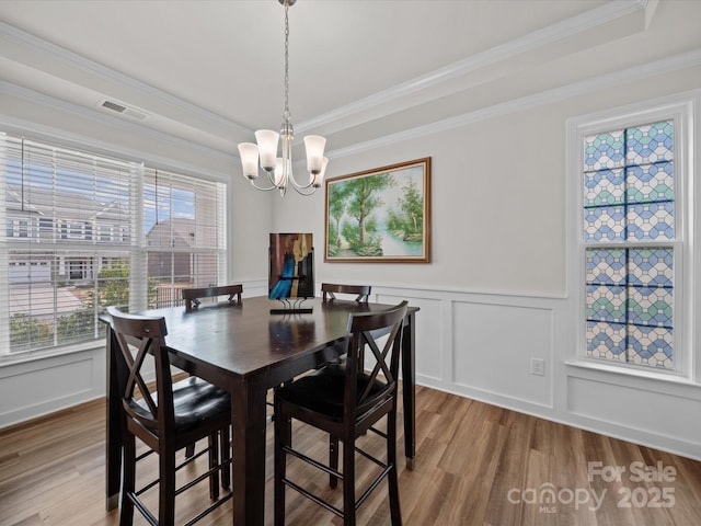 9582 Creighton Rd NW, Concord, NC 28027 - dining room featuring a decorative wall, visible vents, ornamental molding, wood finished floors, and a notable chandelier