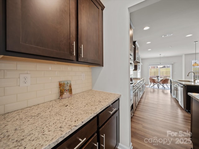 9582 Creighton Rd NW, Concord, NC 28027 - kitchen featuring decorative backsplash, dishwasher, dark brown cabinets, a sink, and light stone counters