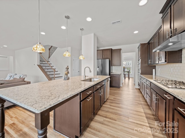 9582 Creighton Rd NW, Concord, NC 28027 - kitchen featuring a large island with sink, dark brown cabinetry, a sink, light wood-type flooring, and stainless steel appliances