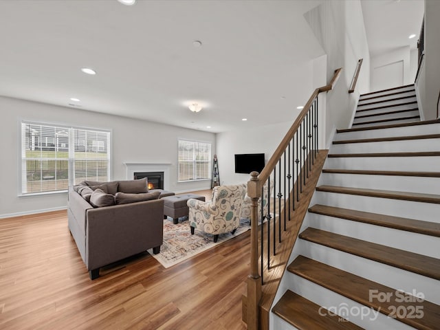 9582 Creighton Rd NW, Concord, NC 28027 - living room with stairs, recessed lighting, baseboards, light wood-style flooring, and a glass covered fireplace