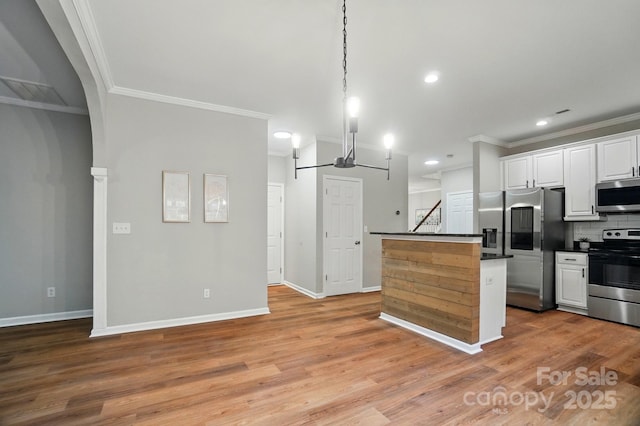 kitchen with a center island, crown molding, dark countertops, white cabinets, and appliances with stainless steel finishes