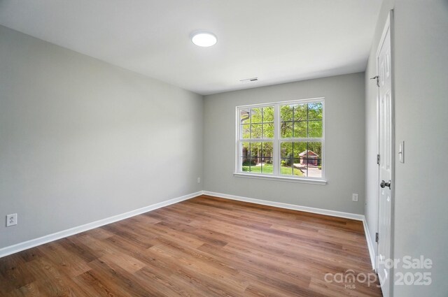 spare room featuring visible vents, baseboards, and wood finished floors