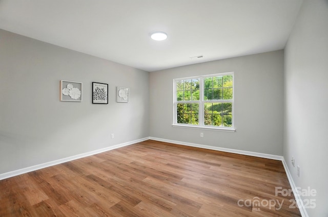 unfurnished room with visible vents, baseboards, and wood finished floors