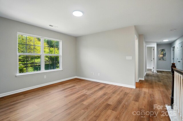 spare room featuring wood finished floors, baseboards, and visible vents