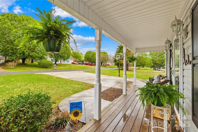 wooden terrace with covered porch and a lawn